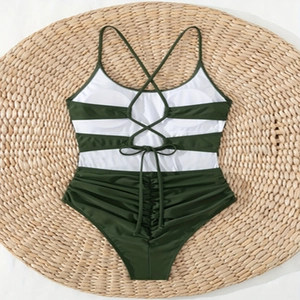 Detail of olive green and white monokini with crisscross back straps on a straw mat