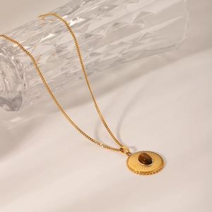 Macro shot of gold stainless steel necklace with round tiger eye stone pendant detail