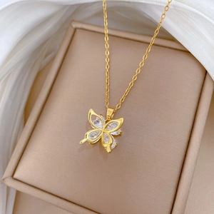 Close-up of a gold butterfly necklace with clear zircon stones on a silk fabric background
