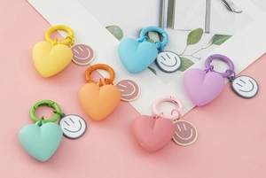 Flat lay of colorful heart and smiley face keychains in six assorted pastel shades