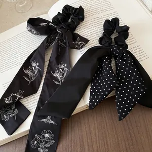 Floral print and polka dot satin bow hair scrunchies with long streamers on book