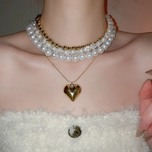 Détail du collier à plusieurs rangs avec perles et pendentif cœur sur un mannequin