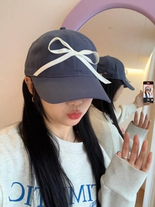 Close-up of navy blue baseball cap with a large white bow in a mirror selfie detail