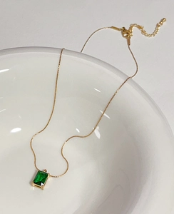 Detail of emerald green rectangular zircon pendant on 18k gold-plated chain