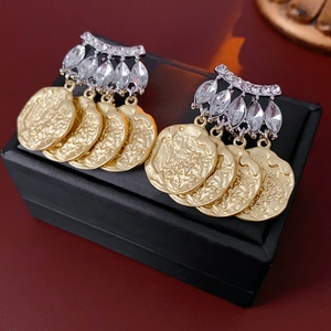 Detail of vintage gold coin tassel earrings with silver base and sparkling rhinestones