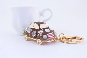 Macro shot of a vintage beetle car keychain featuring cat-eye rhinestones and gold wheels