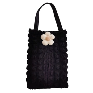Detail of black bubble texture tote bag with a 3D white crochet flower decoration
