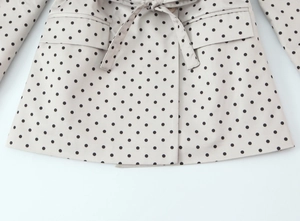 Détail de la veste à pois avec poche et ceinture réglable à la taille ajustée