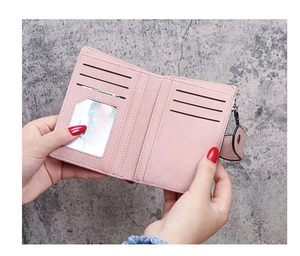 Detail showing pink leather bifold wallet with multiple card slots and clear photo window