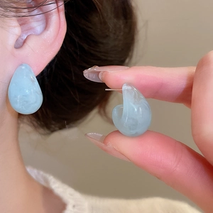 Detailed view of light blue resin drop earrings with marble texture and silver pins