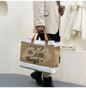 Dettaglio borsa in lino con motivo a cuore e scritta enjoy the little things