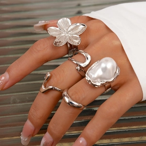 Details des silbernen Ringsets mit Barockperlen und metallischen Blumendesigns