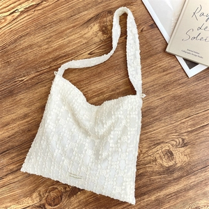 Gros plan du sac bandoulière en dentelle jacquard blanche avec motifs floraux en relief