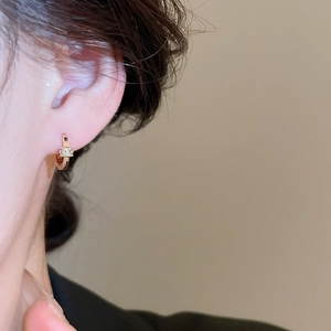 Close-up of 18k gold plated hoop earrings with shimmering zircons on a model's ear