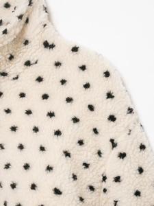 Vue détaillée d'une veste polaire crème douce avec un motif classique à pois noirs