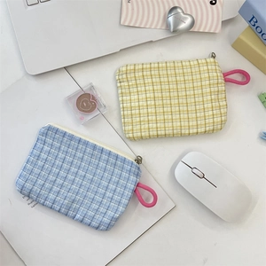 Close-up of blue and yellow plaid pouches with pink loops on a minimalist desk set