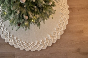 Dettaglio del tappeto per albero di Natale in maglia a trecce color crema con bordi ondulati