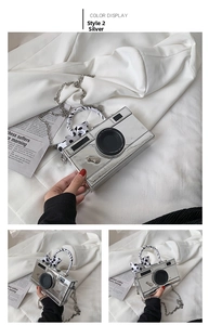 Macro detail of silver camera-shaped crossbody bag with polka dot ribbon and metal chain
