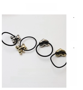 Detail of creative metal bear and heart charms on elastic hair ties in gold and silver
