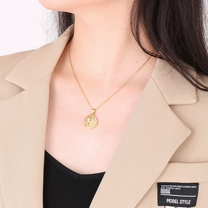 Detail of gold necklace with sun, moon, and star engraved pendant worn by a model