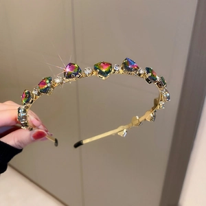 Close-up of golden headband featuring emerald zircon and rainbow gemstones with rhinestones