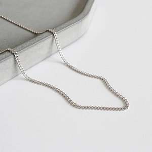 Minimalist S925 sterling silver curb chain necklace displayed on a textured stone tray