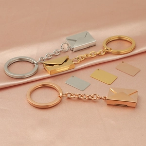 Polished stainless steel envelope pendants in silver, gold, and rose gold on silk fabric