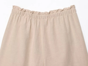 Close-up of khaki linen shorts featuring elastic drawstring waistband and ruffle trim