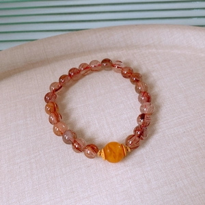 Detail of red rutilated quartz beaded bracelet with a yellow amber center bead