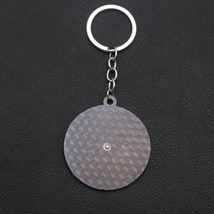 Detailed back view of round metal keychain with silver honeycomb texture on black leather