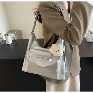 Detail of silver PU leather shoulder bag featuring a chic bow and cloud plush charm