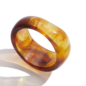 Bracciale largo in resina irregolare con trama a sabbia ambrata su sfondo bianco