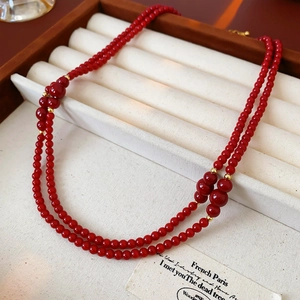 Dettaglio di una collana a due strati con perle di vetro rosse e distanziatori dorati chic