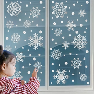 Silver snowflake window clings set featuring a girl decorating a glass window for Christmas