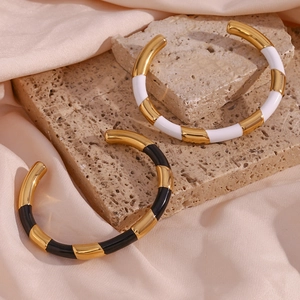 Detail of minimalist 18K gold plated stainless steel bangles with black and white enamel