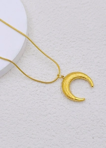 Detailed close-up of golden crescent pendant with honeycomb texture and sleek snake chain