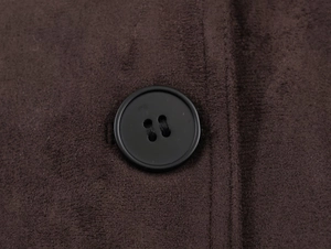 Detail of dark brown faux suede fabric texture and a black round button on a woman's jacket