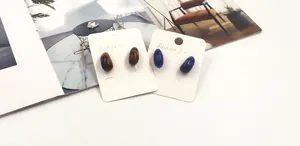 Detail view of water-drop shaped tiger eye and lapis lazuli stud earrings on card