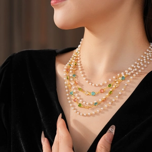Detail of vintage multilayer necklace with pearls and colorful gemstones on a black velvet base
