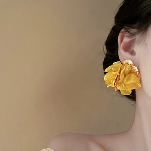 Macro shot of an oversized yellow organza flower earring with golden metallic petals