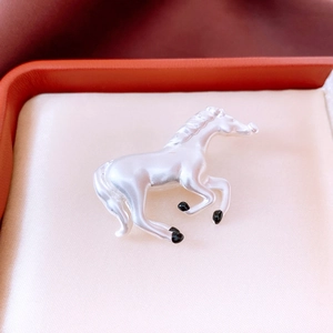 Macro detail of horse brooch with pearlescent finish in a luxury orange jewelry box