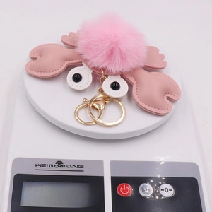Close-up of pink fluffy crab plush keychain on scale showing 25.3g weight detail