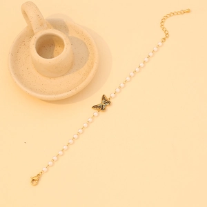 Gros plan sur le pendentif papillon doré et collier de perles blanches avec fermoir réglable