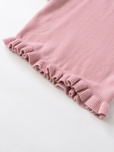 Detail of pink knitwear featuring a ruffled lettuce edge hem and fine soft texture