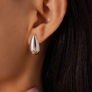 Vue macro latérale d'une boucle d'oreille goutte en argent poli portée par un mannequin