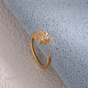 Detail of leaf flower nose ring with gold finish and inlaid zircons on blue fabric