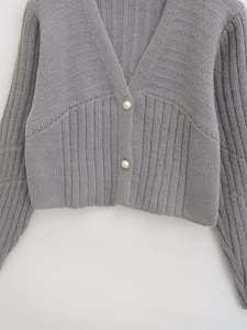 Detail of grey V-neck cardigan featuring elegant pearl buttons and ribbed knit texture