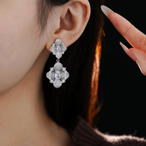 Détail d'une boucle d'oreille losange fleurie sertie de diamants argentés sur un mannequin