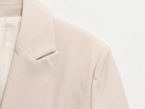 Détail du revers et des épaulettes sur le blazer en sergé beige clair pour femme