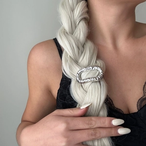 Close-up of a silver hammered metal hair clip styled on a blonde braided ponytail